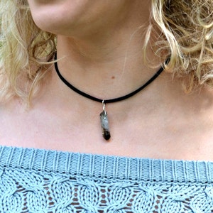 May include: A black choker necklace with a small, clear, grey, and brown crystal pendant.