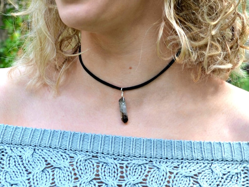 May include: A black choker necklace with a small, clear, grey, and brown crystal pendant.