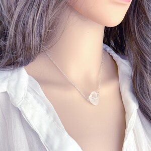 May include: A silver chain necklace with a clear quartz crystal pendant. The pendant is a natural, irregular shape.