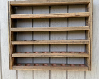 May include: A rustic, wooden wall-mounted spice rack with six shelves. The rack is made of weathered wood, with a natural finish. The bottom shelf has several circular cutouts. The rack is designed to hold spice jars and other small items.