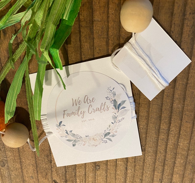 May include: A white card with a round sticker featuring a floral wreath and the text "We Are Family Crafts Est. 2015".