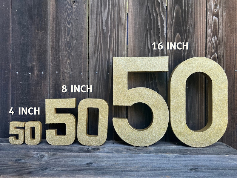 May include: Four gold glitter cardboard numbers, 50, in four different sizes: 4 inches, 8 inches, 16 inches. The numbers are arranged from smallest to largest.