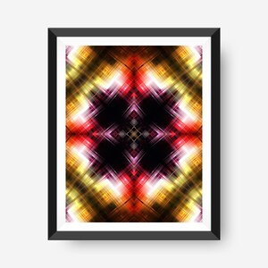 May include: Framed abstract art print with a symmetrical design and a central black square. The artwork displays a vibrant mix of red, yellow, and purple, arranged in a cross-like pattern. The print is enclosed in a black frame.