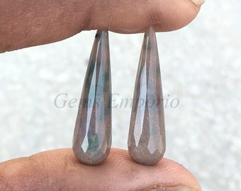 Peut inclure: Deux cabochons de pierres précieuses en forme de larme avec un motif de couleur brun, gris et vert.  Gems Emporio est imprimé sur le fond.