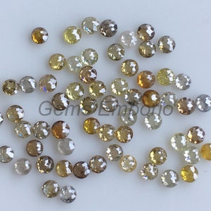 May include: A collection of round, faceted, brown diamonds. The diamonds are scattered on a white surface.