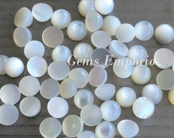 May include: A collection of white iridescent round cabochon gemstones. The stones are smooth and have a pearly sheen.