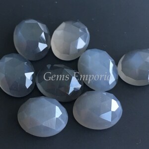 Pode incluir: Dez cabochões ovalados de pedra da lua cinzenta facetados. As pedras são translúcidas e têm um brilho ligeiro.