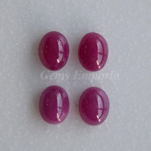 May include: Four oval-shaped, pink gemstones. The gemstones are smooth and polished.