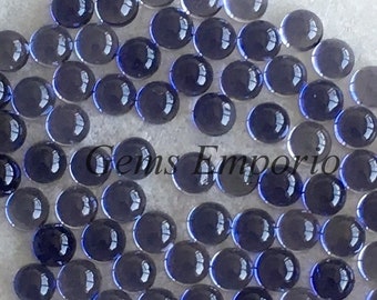 May include: A large group of round, dark blue glass cabochons. The cabochons are arranged in a loose, overlapping pattern. The cabochons are all approximately the same size and shape.