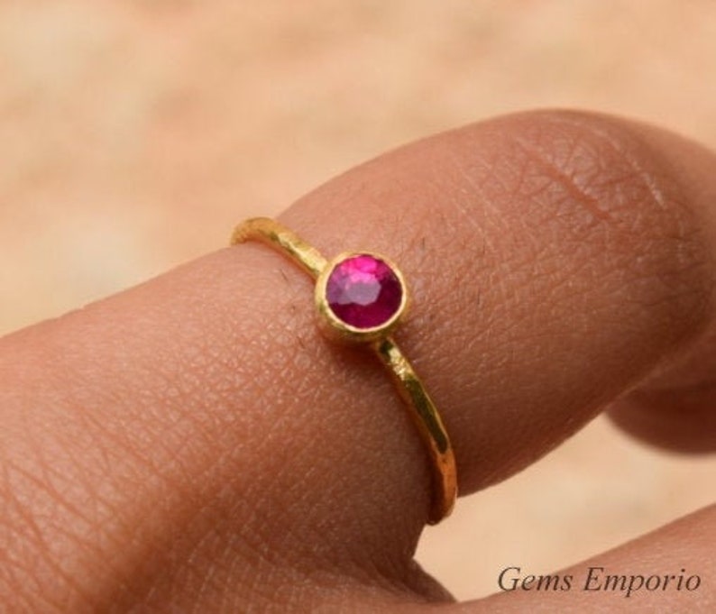 Pu&ograve; includere: Un delicato anello d'oro con una singola pietra preziosa rotonda di colore rosa brillante.