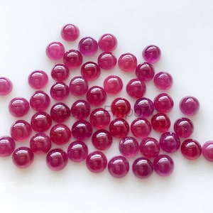 Op de afbeelding: Een verzameling ronde, roze robijn cabochons. De cabochons zijn glad en gepolijst, met een lichte variatie in grootte en tint.