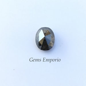 Puede incluir: Una piedra preciosa negra de forma ovalada con un corte facetado. La piedra preciosa est&aacute; colocada sobre un fondo blanco.