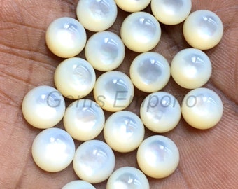 May include: A collection of 18 white mother of pearl cabochons, each with a smooth, round shape and a slightly iridescent finish.