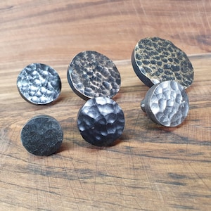 Peut inclure: Cinq boutons ronds en métal martelé de différentes tailles. Les boutons sont noirs, argentés et dorés.