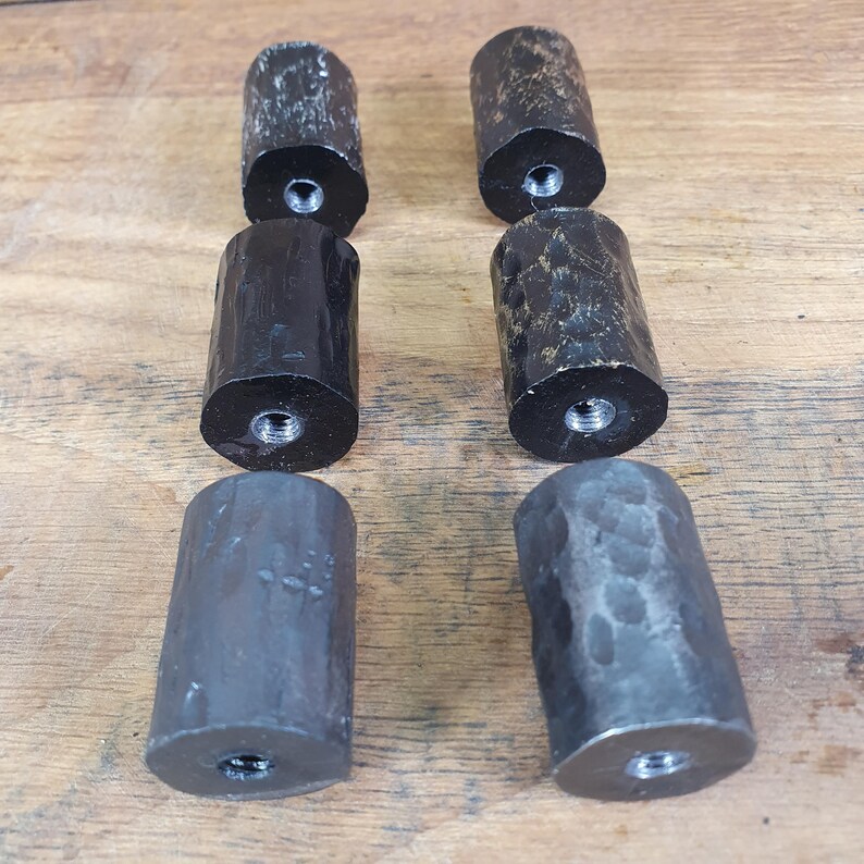 May include: Six black metal drawer pulls with a hammered finish. Three of the pulls have a smooth black finish and three have a distressed black finish.