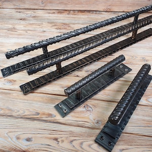 May include: Three black metal door handles with a twisted design. The handles are on a wooden surface.