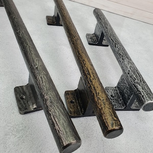 Peut inclure: Trois poignées de porte de style rustique dans des tons de gris et de marron. Chaque poignée a un aspect texturé semblable à du bois et est montée sur une base rectangulaire. Les poignées sont conçues pour un aspect robuste et décoratif.