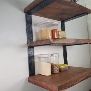 Könnte beinhalten: Ein dreistufiges Holzregal mit dunklen Metallhalterungen. Die Regale sind mit transparenten Kunststoffbehältern gefüllt, die verschiedene Körner und Gewürze enthalten. Das Holz hat einen natürlichen, warmen Farbton.