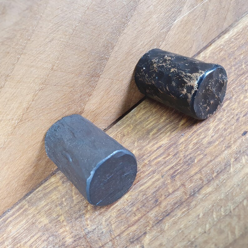 May include: Two black cylindrical cabinet knobs with a distressed finish. The knobs are made of metal and have a slightly rounded shape.