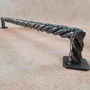 May include: A twisted metal door handle with a square base. The handle is made of a single piece of metal that is twisted into a rope-like shape.