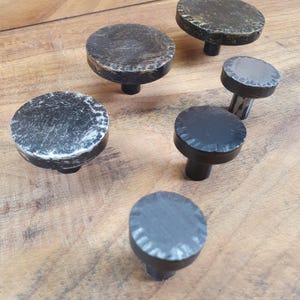 May include: Five black metal drawer pulls with a distressed finish. The pulls have a round top and a short stem.
