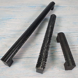 May include: Three black metal cabinet pulls with different lengths and designs. The pulls have a distressed finish.