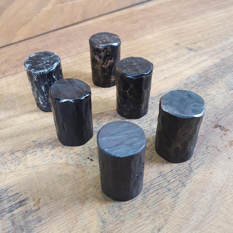May include: Six black metal knobs with a hammered finish. The knobs are round and have a slightly textured surface.