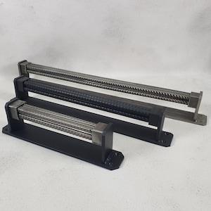 May include: Three black metal door handles with a textured, industrial design. The handles are different sizes and are mounted on black metal plates.