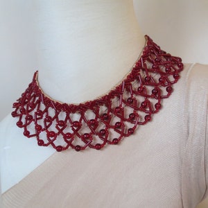 May include: A red beaded choker necklace with a geometric design. The necklace is made of small, round beads that are strung together in a pattern of interlocking squares and triangles.