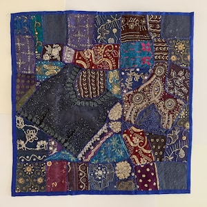 May include: A patchwork quilt with a variety of colors and patterns, including blue, purple, red, and gold. The quilt is made of different fabrics and textures, and it has a unique and eclectic design.