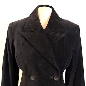 May include: A black velvet blazer with a double-breasted design. The jacket features a notched lapel collar and two visible buttons. The sleeves are long and the garment is displayed on a mannequin.