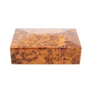 May include: A rectangular wooden box with a glossy finish. The box has a natural wood grain pattern in shades of brown and tan. The lid and sides are smooth and polished, suggesting a decorative or storage item.