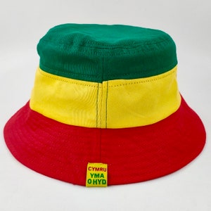 May include: A green, yellow, and red bucket hat with the text "CYMRU YMA OHYD" on the back.