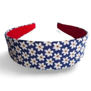 May include: A blue headband with a white floral pattern. The headband has a red underside.