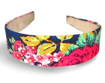 May include: A floral headband with a navy blue background and pink, yellow, and green flowers.