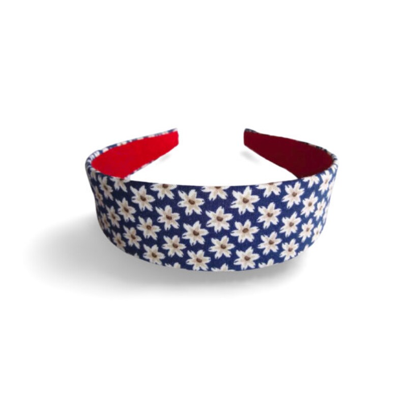 May include: A blue headband with a white floral pattern. The headband has a red lining.