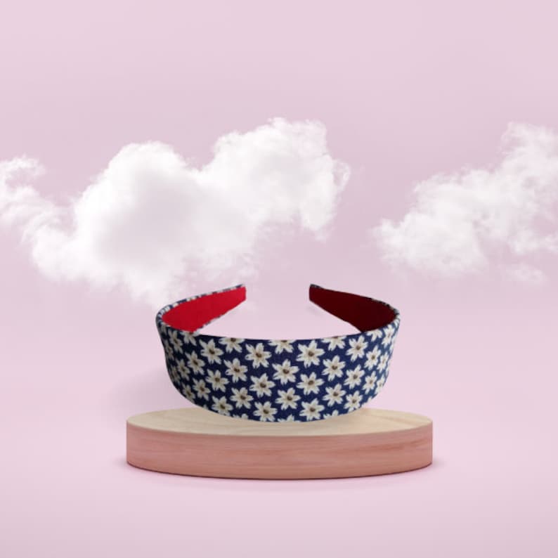 May include: A blue headband with a white floral pattern and a red underside. The headband is on a wooden platform.