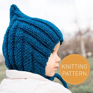 Op de afbeelding: Een blauwe gebreide baby muts met een puntige top en een lange stropdas. De muts is gemaakt met een textuur-steekpatroon.  BREIPATRON.