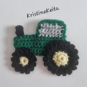 May include: A green and black crocheted tractor applique featuring a grey window section, a black exhaust pipe, and two wheels with black outer rims and cream-colored centers. The text KristineKeita is printed in black above the tractor.