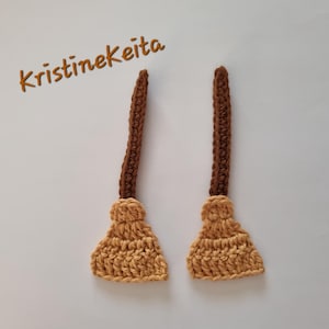 May include: Two handmade crochet brooms with brown handles and tan broom heads. The brooms are displayed on a white background. The text "Kristinekeita" is written in brown cursive in the upper left corner.