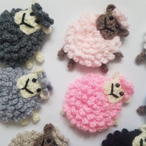 May include: A collection of ten crocheted sheep in various colors, including pink, gray, white, and blue. Each sheep has a white face with black eyes and a black nose.