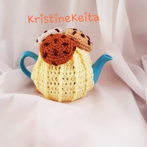 Peut inclure: Une théière bleue avec une housse en crochet jaune, surmontée de biscuits au crochet. Les biscuits sont marron, beige et blancs avec des détails de pépites de chocolat marron. Le texte "KristineKeita" est en orange.