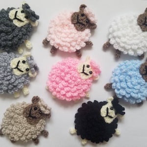 May include: Nine crocheted sheep in various colors, including gray, pink, white, blue, and brown. Each sheep has a fluffy texture and a cute face.