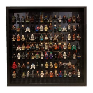 May include: A black framed display case with a clear front showcasing a collection of Star Wars Lego minifigures. The minifigures are arranged in rows and columns, with the Star Wars logo displayed prominently in the center.