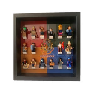 Puede incluir: Una caja de sombra de marco negro con 16 minifiguras LEGO de Harry Potter. Las minifiguras están dispuestas en cuatro filas de cuatro. La caja tiene un escudo de Hogwarts y la palabra "minifiguras" impresa en la parte delantera.