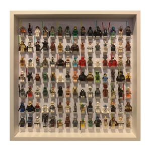 May include: A white frame display case filled with a collection of Star Wars Lego minifigures. The minifigures are arranged in rows and columns, and they include characters from the original trilogy, the prequel trilogy, and the sequel trilogy.