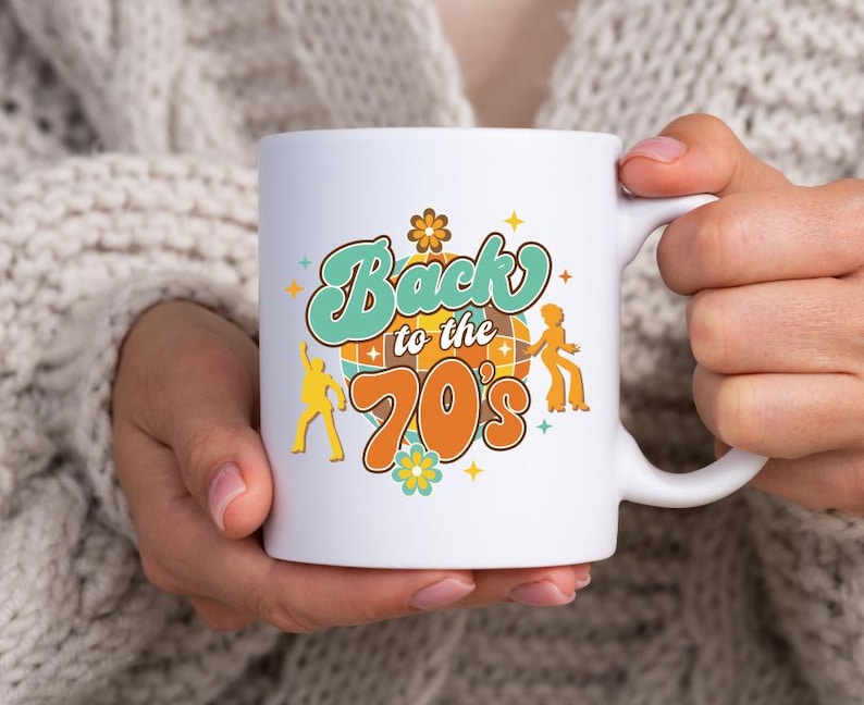 May include: A white ceramic mug featuring a colorful graphic with the text Back to the 70's. The design includes a central disco ball, two dancing figures in yellow, and small flower and star accents in shades of orange, teal, and yellow.