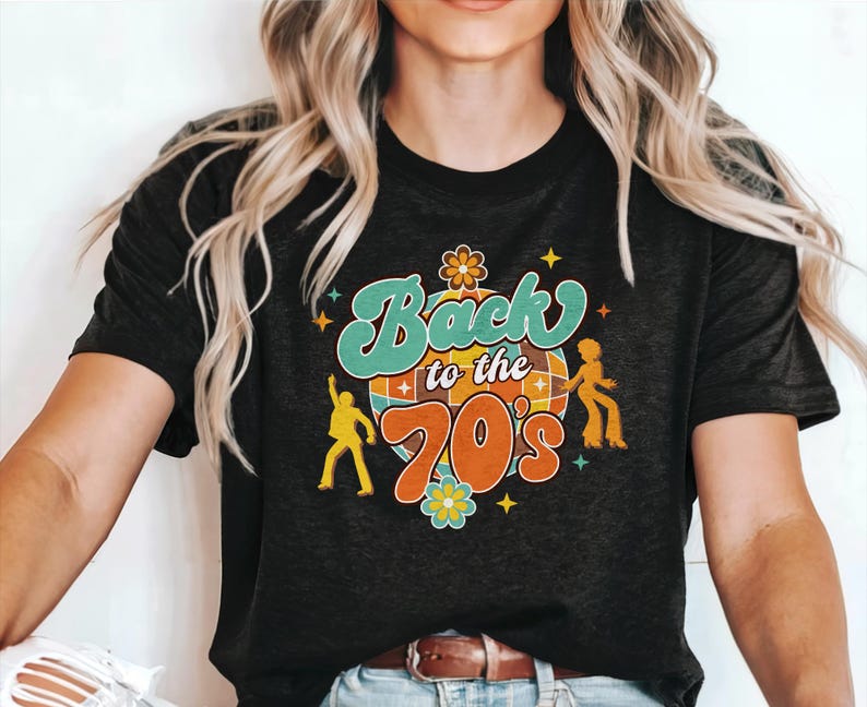 May include: A black short-sleeved t-shirt featuring a graphic print with the text Back to the 70's in teal and orange. The design includes a central disco ball, two yellow dancing figures, and small flower and star accents in various colors.