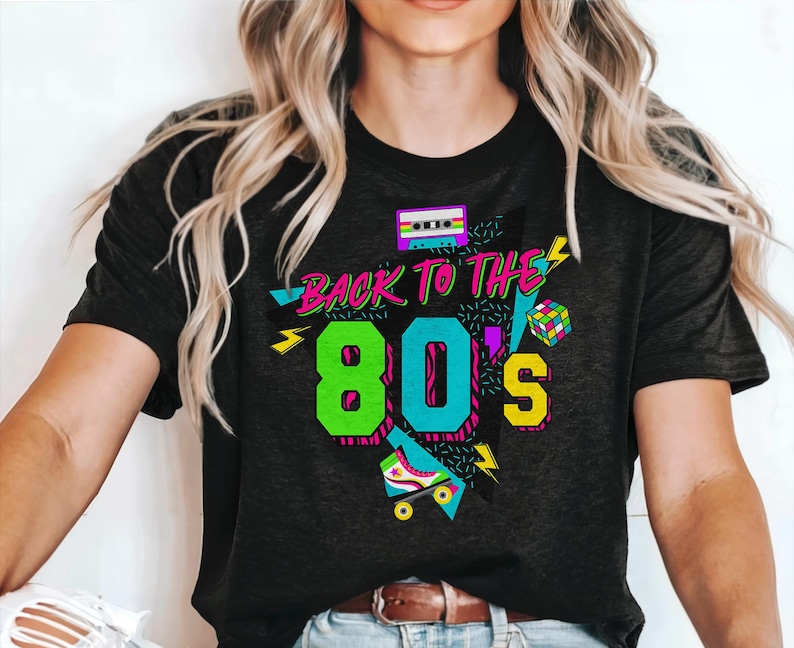 May include: Black t-shirt with a graphic design featuring the text "Back to the 80's" in neon colors with a cassette tape, roller skate, and geometric shapes.