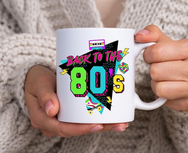 May include: White ceramic mug with a colorful graphic design featuring the text "Back to the 80's" with a cassette tape, roller skate, and geometric shapes.